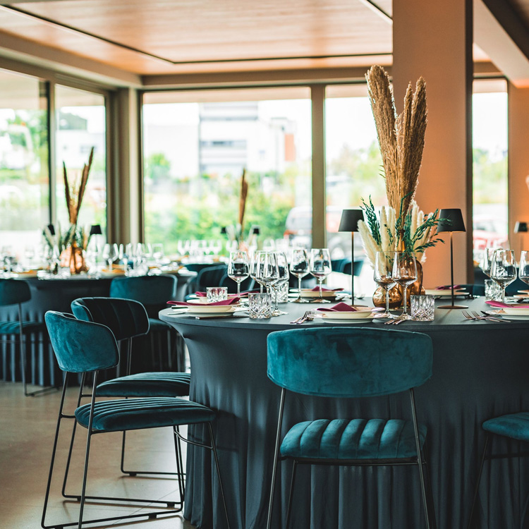 Veranstaltungssaal der LAKESIDE Location mit petrofarbenen Stühlen, dunklen Hussen und elegant gedeckten Tischen